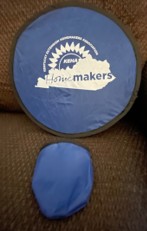 Blue with black border fold up fabric disk shaped flyer that can be used as a pocket fan.